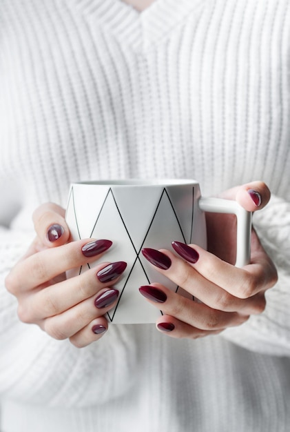 Hands of a young woman with white manicure on nails