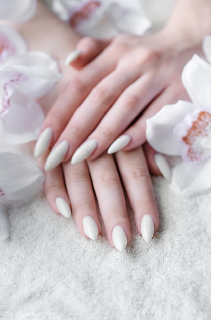 Hands of a young woman with white manicure on nails