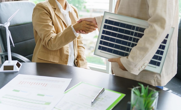 Handshake and business with solar panels green energy Business people working in green eco friendly office business meeting creative ideas for business eco friendly