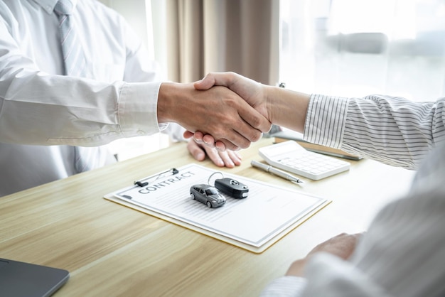 Handshake of customer and salesman after agreement successful of car loan insurance contract buying or selling new vehicle