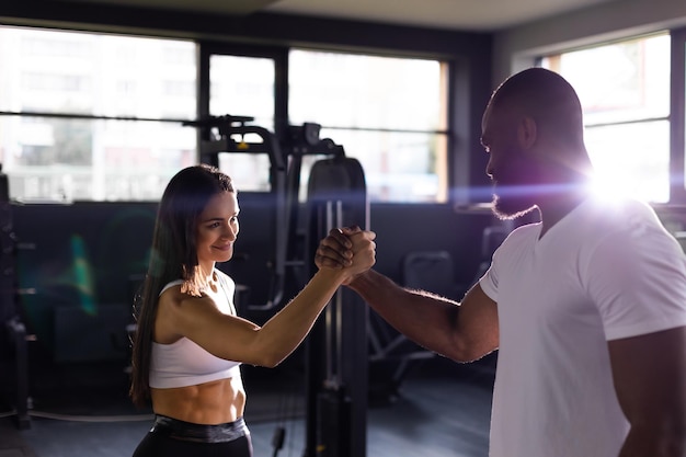 Handshake of sporty african man with woman greeting partner exercise workout at fitness gym