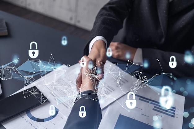 Handshake of two businesswomen who enters into the contract to protect cyber security of international company Padlock Hologram icons over the table with documents