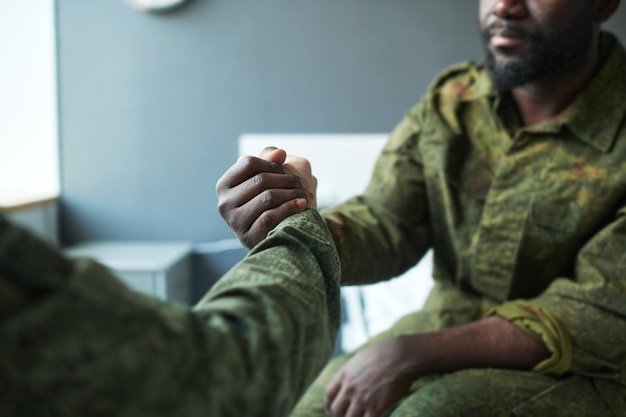 Handshake of two intercultural male buddies in camouflage