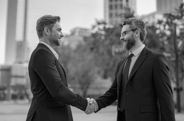 Handshake with partner in the city for greeting Two businessmen shaking hands outdoor Business mens growth strategy Business men with proposal to the client Handshake between two businessmen