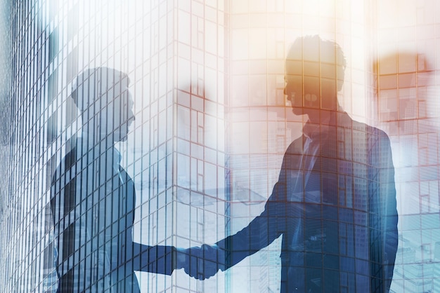 Handshaking business person in office concept of teamwork and partnership double exposure