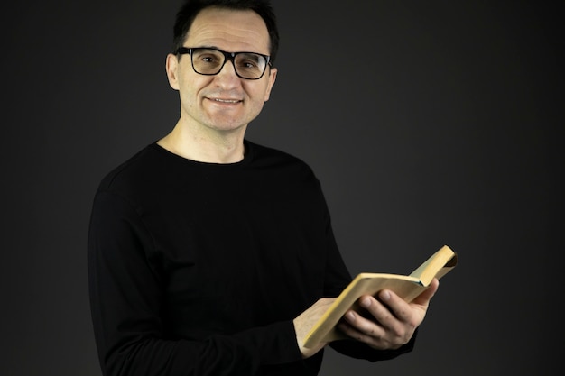 Handsome 40s man with dark hair in glasses holds book in hands