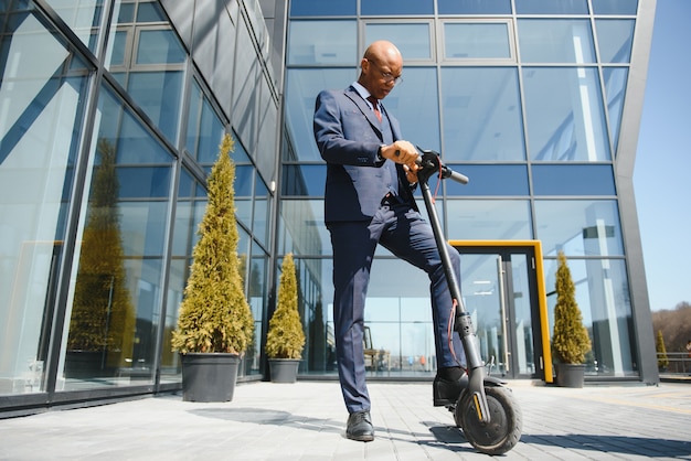 Handsome african businessman riding electric scooter outdoors