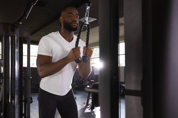 Handsome african man doing heavy weight exercise for triceps in the gym