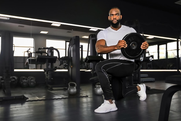 Handsome african man is working out with dumbbells at gym