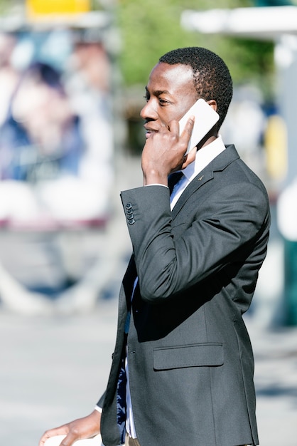 Handsome african man with mobile phone and fixed gear bicycle in the street.