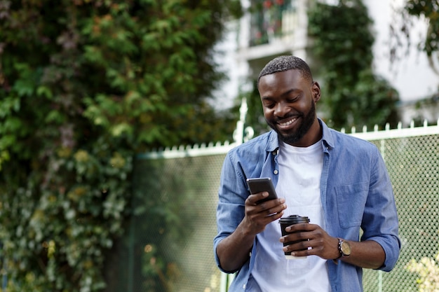 Handsome Afro-American man using smartphone and smiling.