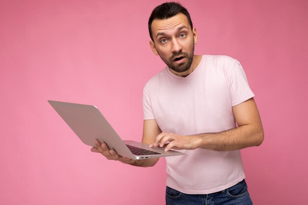 Handsome amazed and surprised man holding laptop computer