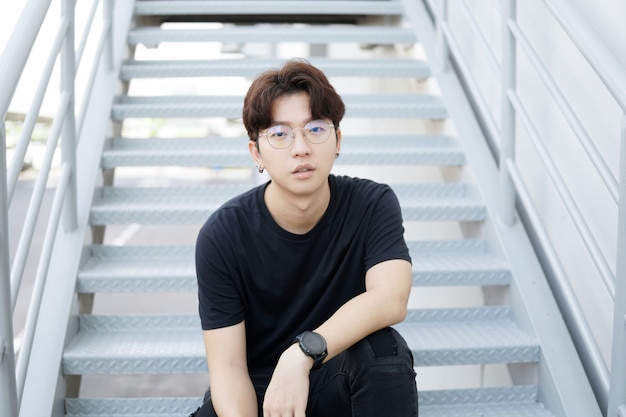 Handsome asian CASUAL glasses man sit on a staircase and smile posing 