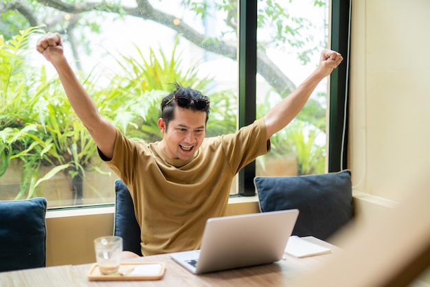 A handsome Asian man expresses his joy after checking his job application results online to see if he has been selected for a job