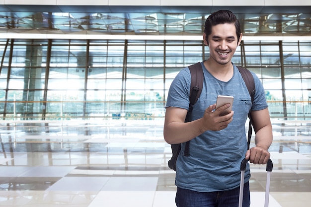 Photo handsome asian man traveler with suitcase holding smartphone