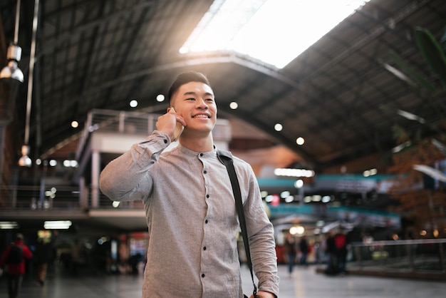 Photo handsome asian man using mobile in the train station. communication concept.