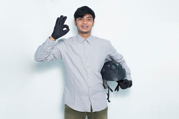 Handsome asian man with a motorcycle helmet showing a thumbs up ok gesture on white background