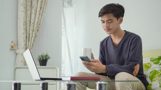 Handsome asian man working from home enjoying a drink