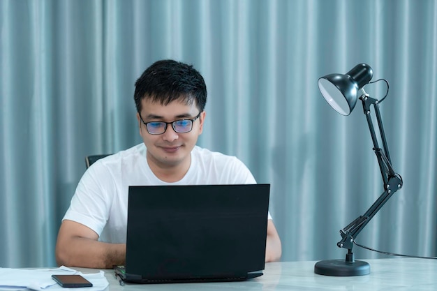 Handsome asian man working at homeWork from home concept Jobs You Can Do From Anywhere in the WorldUse a computer to work with a remote control method