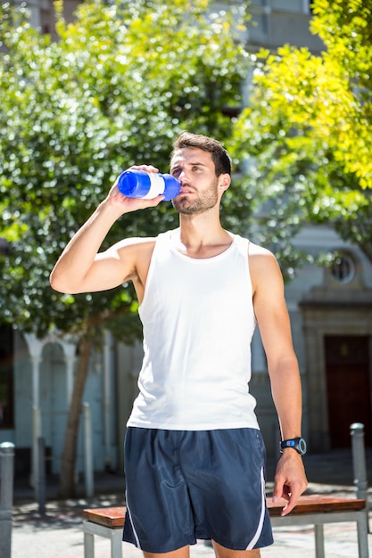 Handsome athlete drinking out of bottle