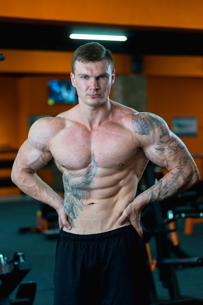 Handsome athlete in the gym demonstrates the pumped up muscles. sports lifestyle.