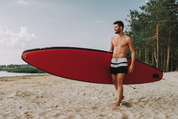 Handsome Athletic Guy With Surf Standing On Beach.