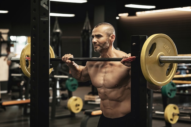 Handsome bearded bodybuilder during his workout with a barbell in the gym