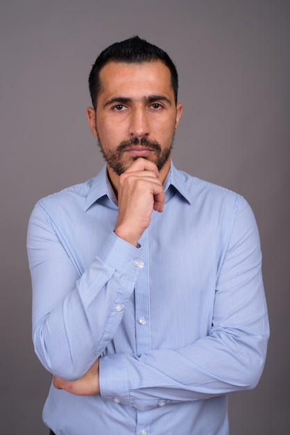 Handsome bearded businessman against gray wall