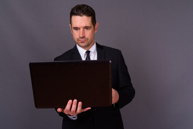 handsome bearded businessman in suit against gray wall