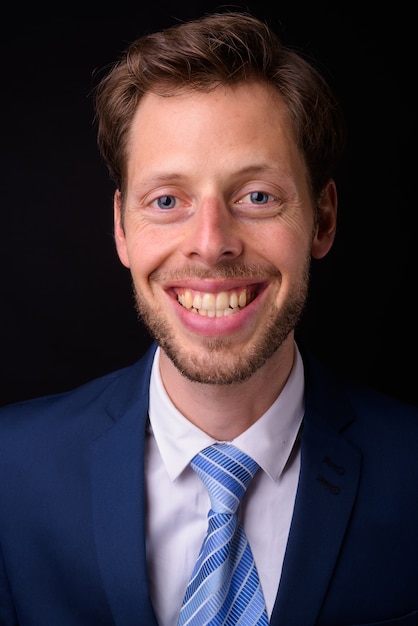 handsome bearded businessman with brown hair wearing suit against black space