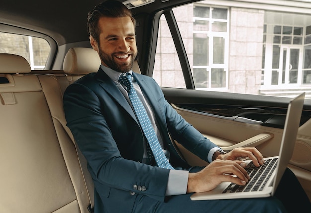 Handsome bearded caucasian male laughing at the laptop in auto