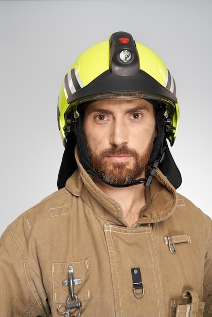 Handsome bearded fireman in workwear looking at camera portrait of brave serious male firefighter in