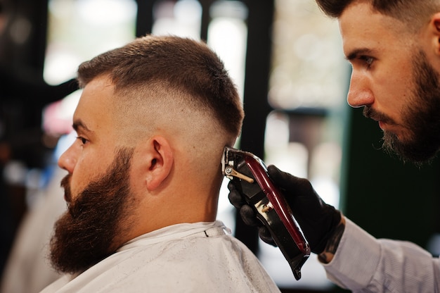 Handsome bearded man at the barbershop, barber at work.