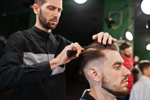 Handsome bearded man at the barbershop, barber at work.