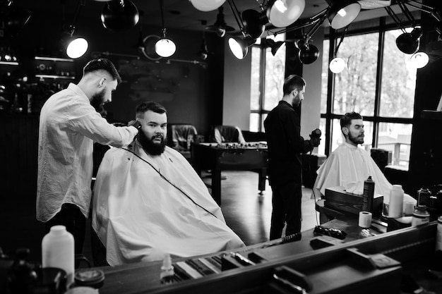 Handsome bearded man at the barbershop barber at work