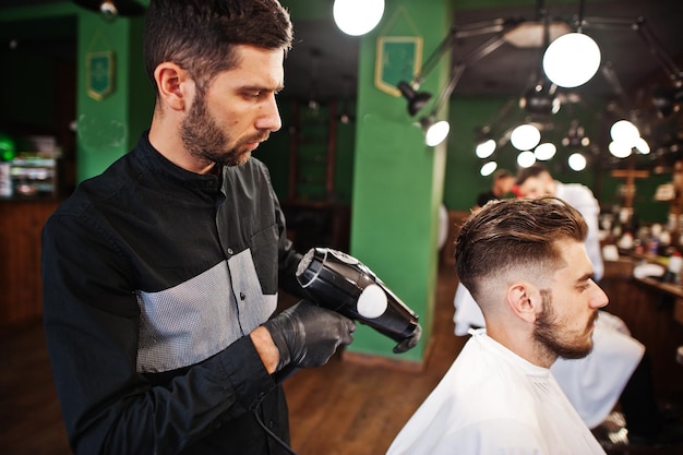 Handsome bearded man at the barbershop barber at work