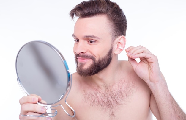 Handsome bearded man cleans his ear with a cotton swab or ear sticks