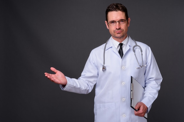  handsome bearded man doctor with eyeglasses against gray wall