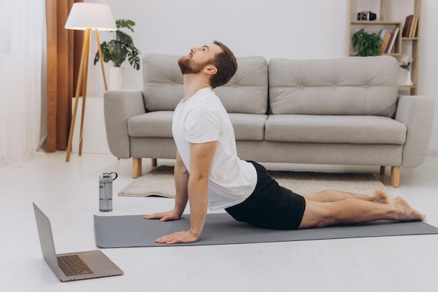 Handsome bearded man doing hamstring stretch exercise at home