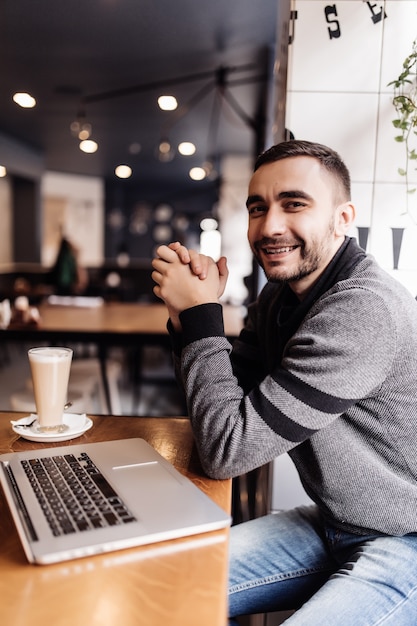 Handsome bearded man drinking coffee while working in a cafe