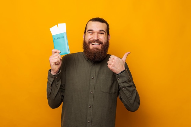 Handsome bearded man is showing thumb up while holding a passport