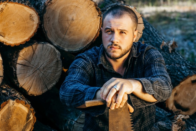 Handsome bearded man near wood logs