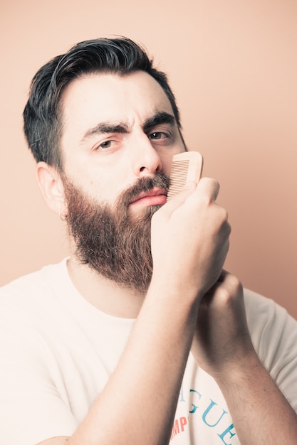 Handsome bearded man shaving his beard, Young caucasian bearded man trimming beard in home during quarantine. Lifestyle concept.