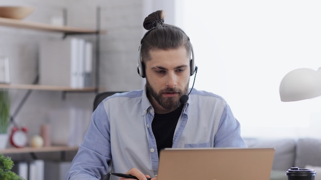 Handsome bearded man studying online using laptop web camera