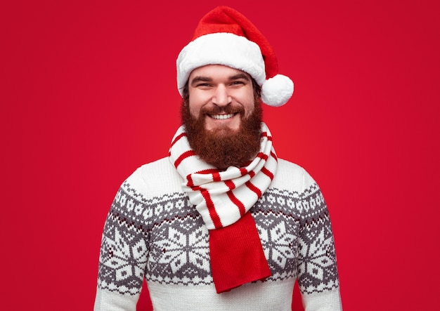 Handsome bearded man wearing sweater with colorful Santa hat