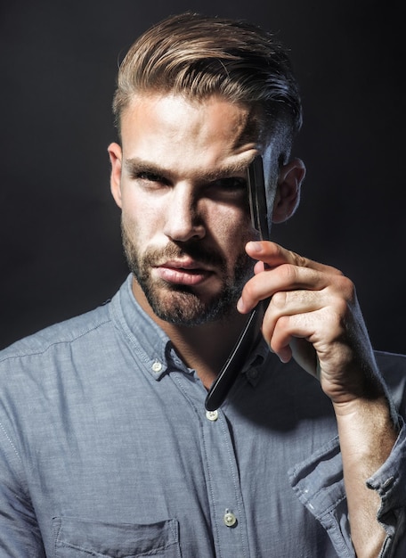 Handsome bearded man with straight razor barbershop equipment shaving in barber shop