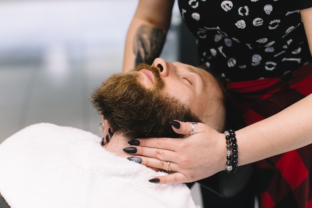 Handsome bearded and moustache man has shave in barbershop.