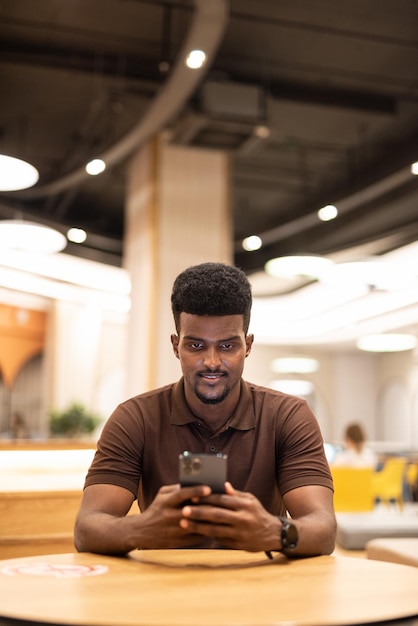 Handsome black man at coffee shop using mobile phone