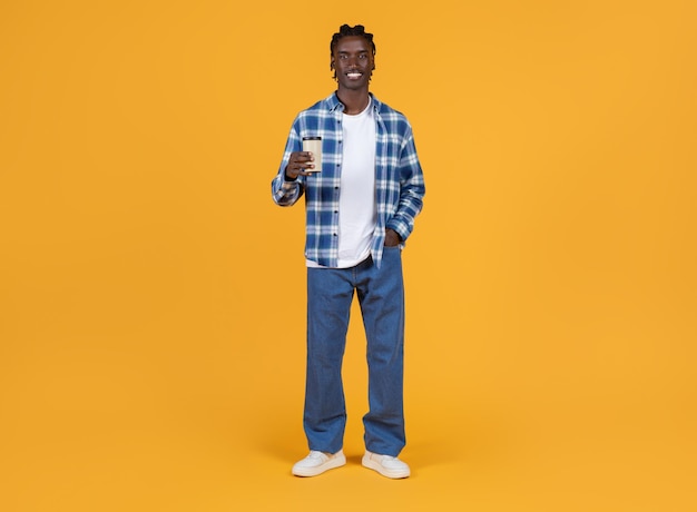 Handsome black man holding takeaway coffee in hand and smiling at camera