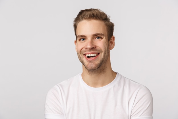 Handsome blond guy with blue eyes and white T-shirt smiling